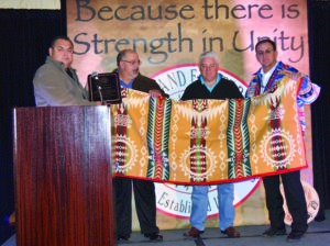 EBCI tribal leaders accept a plaque and Pendleton blanket on behalf of tribal elder Jerry Wolfe who was honored by USET on Monday, Feb. 4.  Shown (left-right) are Birdtown Rep. Tunney Crowe, Big Cove Rep. Perry Shell, Chairman Jim Owle and USET president Brian Patterson.  (USET photo) 