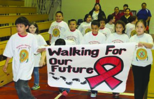 New Kituwah Academy students Donnavin Groenewold (left) and Haley Smith carry a banner for an HIV Awareness Walk at the old Cherokee High School gymnasium on Thursday, March 21.  (SCOTT MCKIE B.P./One Feather)