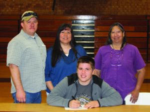 EBCI tribal member Will Ferguson (seated) signs a letter of intent on Wednesday to play football for Southern Virginia as his family looks on including (standing left-right) his father, Neil Ferguson; his mother, Juliet Ferguson; and aunt Iva Mills.  