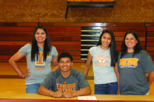 Greg Tisho (seated) signs a letter of intent as a preferred walk-on with the University of Tennessee football program during a ceremony at Swain County High School on Wednesday, May 8.  He is shown with his family (left-right) including: sister Alea Tisho, sister Shay Tisho and mother Libbi Swayney.  (SCOTT MCKIE B.P./One Feather) 
