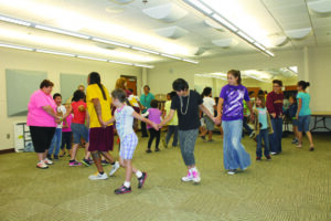 Micah Swimmer (left in yellow shirt) leads the dance class in the Friendship Dance at Cherokee Elementary’s Cultural Summer School held recently. 