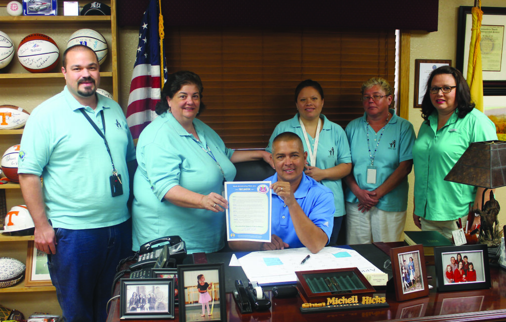 Principal Chief Michell Hicks (seated) signed a proclamation on Friday, Aug. 2 designating August as Breastfeeding Awareness Month in Cherokee.  This is in conjunction with World Breastfeeding Month designations in over 174 countries.  Shown (left-right) at Friday’s signing are, back row – Brian Owle, EBCI WIC administrative assistant; Julie Maney, EBCI WIC manager; Tina Hornbuckle, EBCI WIC breastfeeding peer counselor; Mary Maney, EBCI WIC processing specialist; and Vickie Bradley, RN, EBCI Deputy Health Officer; seated – Chief Hicks.  (SCOTT MCKIE B.P/One Feather) 