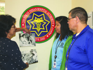 Sarah Sneed (left) looks over old photos of Cherokee Indian Hospital employees with Lucretia Dawkins and Richard French.  (CIH photo) 