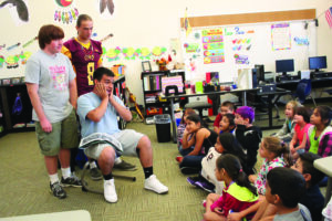 Jalon Lossiah (seated) reads to 2nd graders from Ms. Littlejohn’s class at Cherokee Elementary School on Friday, Aug. 23 as E.J. Carroll and Darren Swayney look on.  The 2nd graders are shown (left-right) – first row – Olivia Swayney, Kalina Hicks, Ileyeni Wolfe; second row – Dillon Bigwitch, Trevan Lambert, Zebe Rattler, Kiersten Zell; and third row – Jaylynn Brady, Kelly Pete and Julia Gonzalez.  (CHS photo)