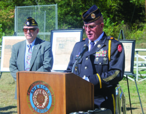 As Commander Lew Harding (left), Steve Youngdeer American Legion Post 143, looks on, Warren Dupree, Post 143 service officer, reads an account of the horrors Rogers endured on the Bataan Death March and in several Japanese prison camps. 