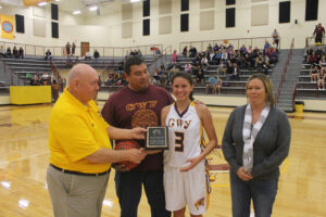 Cherokee athletic director Willis Tullos (left) presents a plaque to junior Kendall Toineeta (2nd from right) on Friday, Nov. 22 moments after she scored her 1,000th point as a Lady Brave as her parents Bruce (2nd from left) and Sunshine Toineeta (right) look on.  