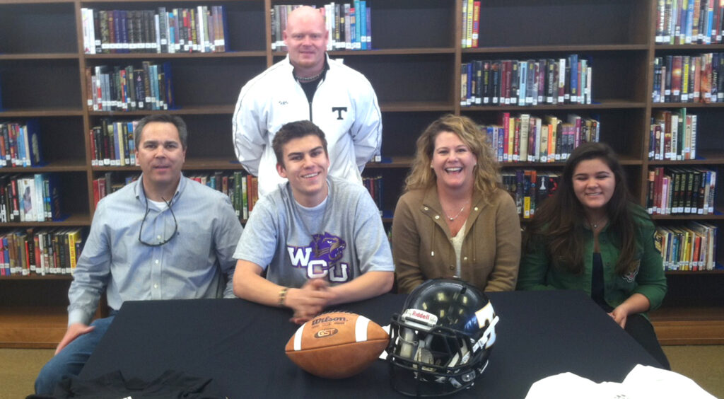 Lambert (seated 2nd from left), flanked by his family, signs a letter of intent to play football at Western Carolina University this fall.  