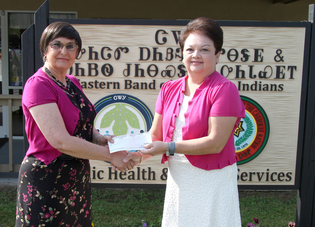 TCGE donates to HIV event  Jo Blaylock (right), Harrah’s Cherokee vice president of human resources, presents a donation check for $2,300 from the Tribal Casino Gaming Enterprise and Harrah’s Cherokee to Aneva Turtle-Hagberg, EBCI Public Health and Human Services health operations director, on Wednesday, May 21.  The donation will be used to help fund the Prevention is Caring Island Celebration, an HIV awareness event, set for Friday, June 27 on the Oconaluftee Island Park.  (SCOTT MCKIE B.P./One Feather)  