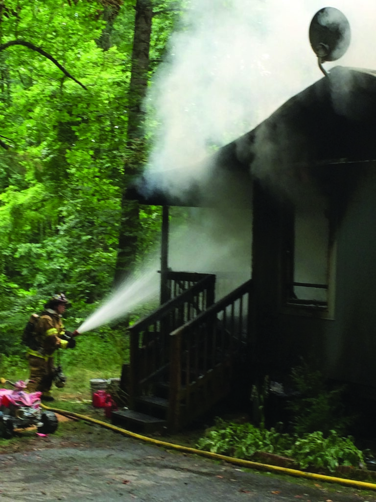 A Cherokee Firefighter works to contain a house fire on Tooni Branch Rd. on Thursday, July 10.  (Photo courtesy of EBCI Public Safety) 