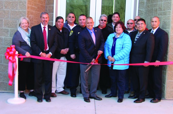 Principal Chief Michell Hicks cuts the ribbon to officially open the EBCI Justice Center on Wednesday, Dec. 17.  Shown (left-right) front row – Cherokee Chief Justice Bill Boyum, Chief Hicks, Chairwoman Terri Henry, Cherokee County – Snowbird Rep. Adam Wachacha and Pepper Taylor; middle row – Painttown Rep. Tommye Saunooke, Vice Chairman Bill Taylor, Cherokee Chief of Police Ben Reed, Vice Chief Larry Blythe and Wolfetown Rep. Bo Crowe; back row – Birdtown Rep. Tunney Crowe, Birdtown Rep. Albert Rose and Big Cove Rep. Perry Shell.  (SCOTT MCKIE B.P./One Feather photos) 