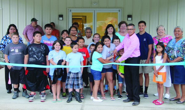 Principal Chief Michell Hicks (center), surround by Painttown Community members and tribal youth, cuts the ribbon to officially open the new Painttown Community Building on Friday, Aug. 14.  (SCOTT MCKIE B.P./One Feather photos)