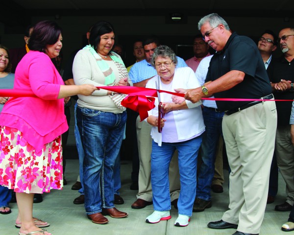 Surrounded by tribal leaders and community members, Gunnie Bradley (center) cuts the ribbon to officially open the new Cherokee Children’s Home on Friday, Aug. 14.  (AMBLE SMOKER/One Feather) 