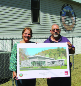 Big Cove representatives Teresa McCoy and Perry Shell hold a rendering for the new Big Cove Day Care Center while standing in front of the existing modular building.  
