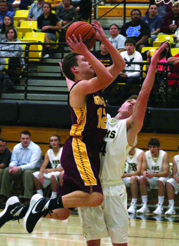 Steven Straughan (#12), Braves senior forward, goes for a shot over Hayesville’s Tyler Leek (#4) in a game at Hayesville on Tuesday, Dec. 15.  Straughan, who fouled out in the second half, ended the game with 5 points and 1 rebound.  (SCOTT MCKIE B.P./One Feather)  
