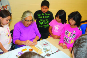 Sharon McCoy (seated center) demonstrates loom beadwork during Arts & Crafts Day.  (Photos courtesy of Cherokee Elementary School) 