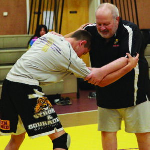 Wrestling Coach John Hohmann demonstrates a takedown technique with Anthony Toineeta at the Cherokee Life Recreation wrestling clinic on Friday, July 15.  (AMBLE SMOKER/One Feather) 