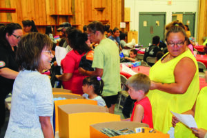 Juanita Wilson (left), EBCI director of Cherokee County and Snowbird services, helps distribute school supplies during the Back-to-School Bash, hosted by the Office of the Principal Chief, at the Cherokee Indian Fairgrounds on Wednesday, Aug. 3. (SCOTT MCKIE B.P./One Feather) 