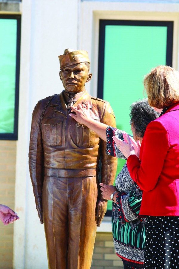 PROUD NIECE: With Cynthia Breyfogle (right), Charles George VA Medical Center director, looking on, Patty Buchanan, George’s niece, touches the Medal of Honor medal on the bronze statue. (SCOTT MCKIE B.P./One Feather) 