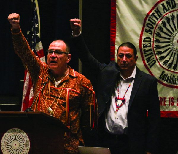 Brian Patterson (left), USET president, and David Archambault II, Standing Rock Sioux Tribe (SRST) chairman, stand with their fists raised during this morning's Opening Ceremonies of the USET Meeting in a show of solidarity for the SRST's fight against the Dakota Access Pipeline. Chairman Archambault addressed the crowd and gave an update on the Pipeline. (SCOTT MCKIE B.P./One Feather) 