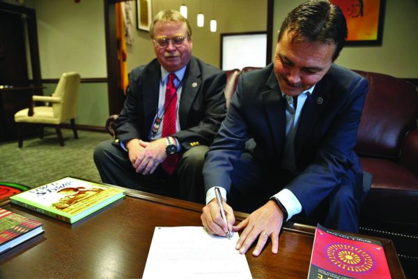 As EBCI Attorney General Danny Davis watches, Principal Chief Patrick Lambert signs a settlement agreement on Monday, Oct. 31 in the Ramah Class Action Settlement whereby the Eastern Band of Cherokee Indians will receive $1.2 million.  (EBCI Communications photo) 