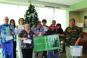 Russell Reed (2nd from right) donated 24 Pediatric activity bags on Thursday, Dec. 8 to the Cherokee Indian Hospital to be used for children admitted there. Shown (left-right) are - Matt Berry, Sonya Wachacha, Bambi Sneed, Dawn Nations, Ginger Arkansas, Tammy Phillips, (back) Jennifer Corriner, LouAnne Shaw – Russell’s mother, Russell Reed, and John Reed – Russell’s father. (Photo by Sheyahshe Littledave) 